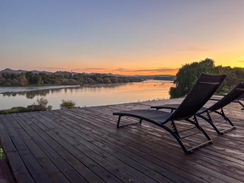 two chairs sitting on a wooden deck overlooking a river at Tzamenkomst River Lodge in Colesberg