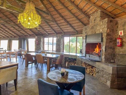 a restaurant with tables and chairs and a fireplace at Tzamenkomst River Lodge in Colesberg