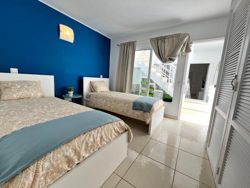 a bedroom with two beds and a blue wall at Casa Oda Seaview in Puerto del Carmen