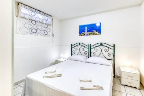 a white bedroom with a large bed with white sheets at Leucos in Leuca