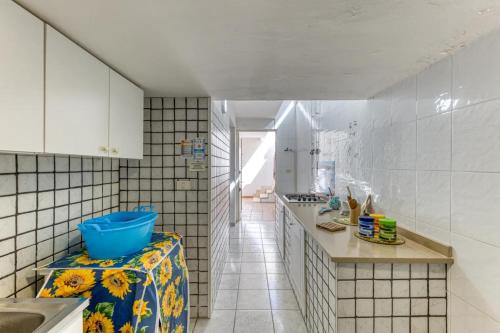 a kitchen with white tiled walls and a blue bowl on a counter at Leucos in Leuca