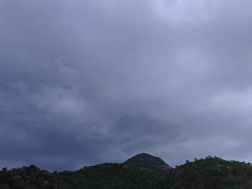 a group of green mountains with a cloudy sky at Agnisthala Guest House in Tiruvannāmalai