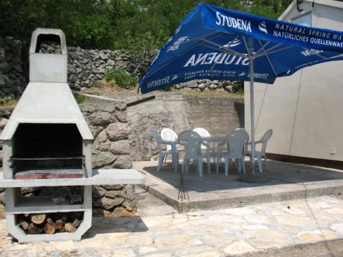 a table and chairs with an umbrella next to a grill at Ferienhaus für 6 Personen ca 50 m in Jablanac, Adriaküste Kroatien Kvarner Bucht in Jablanac