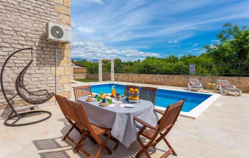 a patio with a table and chairs next to a pool at 3 Bedroom Gorgeous Home In Cabrunici in Čabrunići