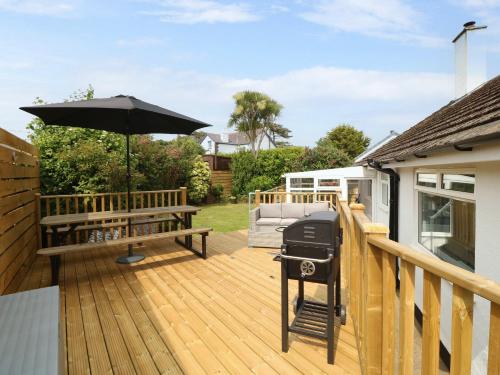 a deck with an outdoor grill and a bench at Haul a Gwynt in Benllech