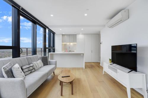a living room with a couch and a kitchen with windows at 2 Bedrooms Apt in Boxhill Centre with free parking in Box Hill