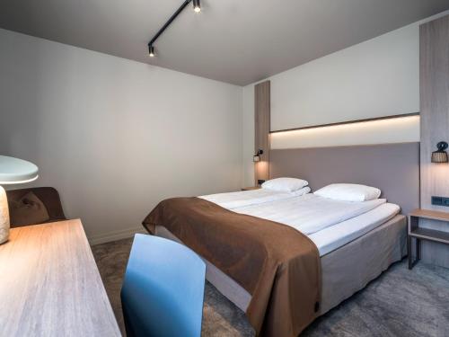 a bedroom with a large bed and a blue chair at Quality Hotel Saga in Tromsø
