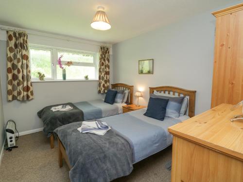 a hotel room with two beds and a desk and window at 9 Manorcombe Bungalows in Callington