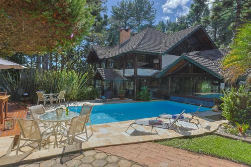 a house with a pool and a table and chairs at Pousada Cantos e Contos in Monte Verde