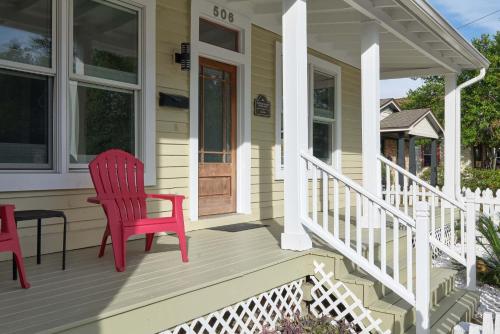 a red chair sitting on the porch of a house at Beautiful Historic Downtown Pensacola Charmer - Hot Tub in Pensacola