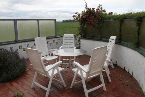 four chairs and a table on a brick patio at Altes Deichbauernhaus mit Scheune, Garten und zwei Etagen in Nieuwvliet