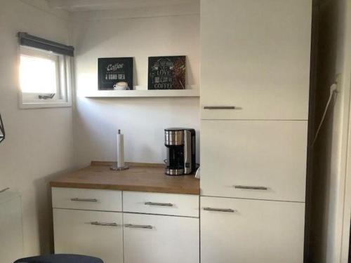 a kitchen with white cabinets and a coffee maker at Hundefreundliches Chalet Meise in Wervershoof