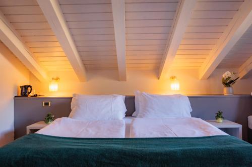 a bedroom with a bed with white sheets and pillows at Hotel Binelli in Pinzolo