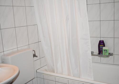 a white bathroom with a shower curtain and a sink at Ruhiger Vorort Bern kostenloses Parken 6km Zentrum in Zollikofen