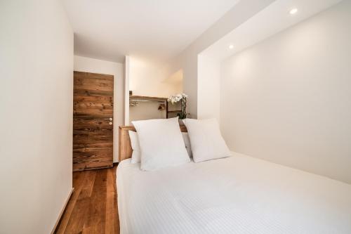 Cette chambre comprend un lit avec des draps blancs et du parquet. dans l'établissement Apartment Poppy Les Gets - by EMERALD STAY, aux Gets