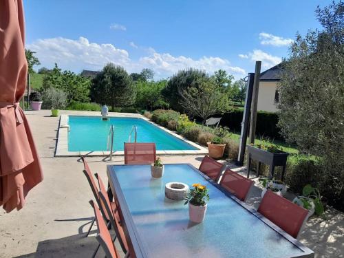 une table et des chaises devant une piscine dans l'établissement Maison a côté du pal, à Saligny-sur-Roudon
