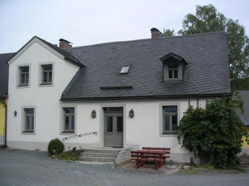 ein weißes Haus mit einer Bank davor in der Unterkunft Hammerschloss Unterklingensporn in Naila