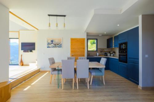 una cucina con mobili blu e un tavolo e sedie in legno di Villa & Spa Kyo-Alpes, piscine intérieures privées-Belledonne a La Combe-de-Lancey