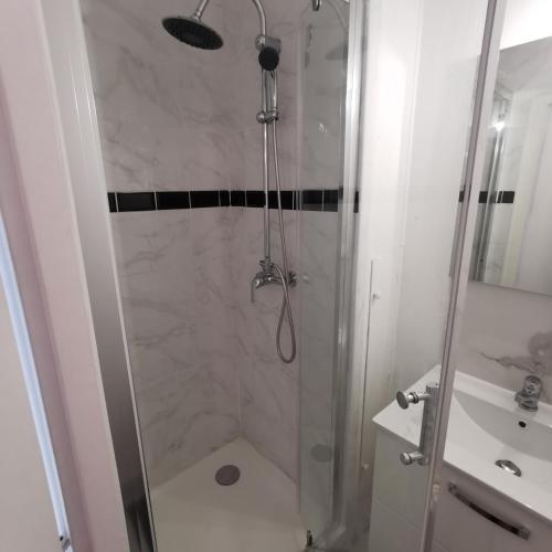 une douche avec une porte vitrée à côté d'un lavabo dans l'établissement Chambre confort Saint Marceau, à Orléans