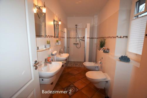 a bathroom with two toilets and a sink and a shower at Ferienhaus MEERzeit in Hohwacht