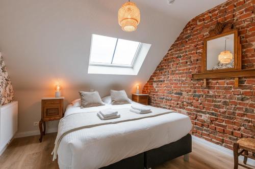 a bedroom with a brick wall and a bed at Huswell - Authentic holiday home in the countryside in Beernem