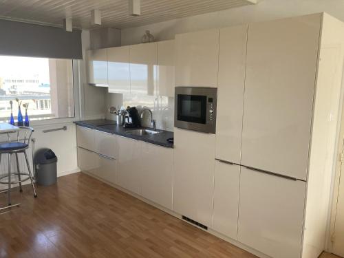 eine Küche mit weißen Schränken und einer Mikrowelle in der Unterkunft het Zeehuisje in Egmond aan Zee