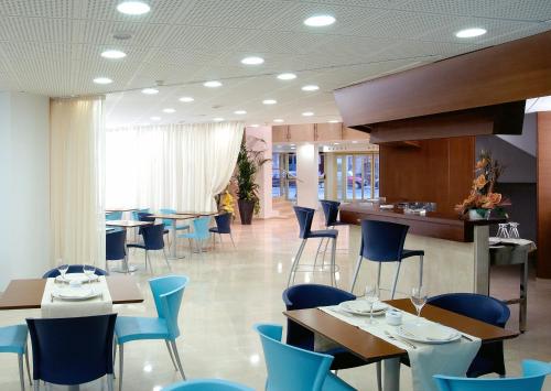 un restaurante con mesas y sillas azules y un bar en Hotel Murrieta en Logroño