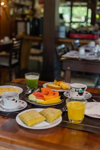 a table with plates of food and cups of orange juice at Pousada Cantos e Contos in Monte Verde