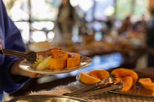 a person holding a plate of fruit on a table at Pousada Cantos e Contos in Monte Verde