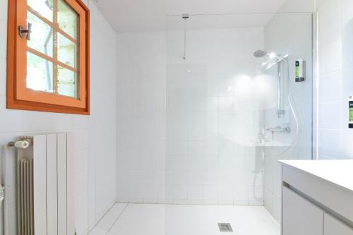 a white bathroom with a shower and a window at Logis L'Auberge de Larressingle in Larressingle