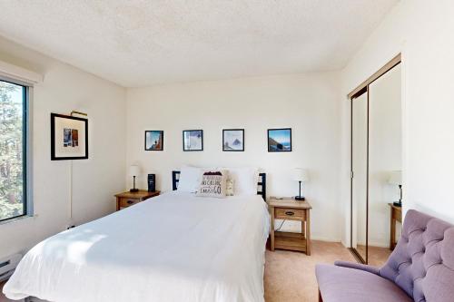 een witte slaapkamer met een bed en een stoel bij Ski Bowl Condos Unit 518 in Truckee