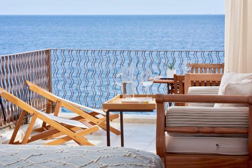 a balcony with a table and chairs and the ocean at St. Nicolas Bay Resort Hotel & Villas in Agios Nikolaos