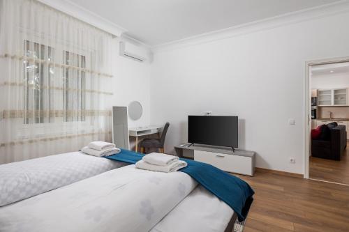 a white bedroom with two beds and a television at Amelia & Julia apartments in Rijeka