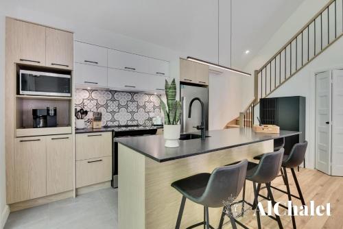 a kitchen with a counter and chairs in it at Sunset - Cosy boisé - Spa in Pont-Rouge