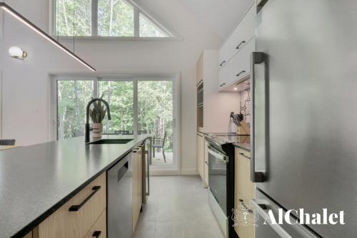 a kitchen with a counter top and a large window at Sunset - Cosy boisé - Spa in Pont-Rouge