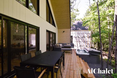 an outdoor patio with a black table and chairs at Sunset - Cosy boisé - Spa in Pont-Rouge