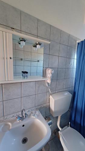a bathroom with a sink and a toilet and a mirror at Ostria Seaside Apartments in Patra