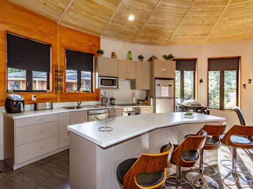 a kitchen with wooden ceilings and a large island with chairs at Turoa Yurt - Ohakune Holiday Home in Ohakune