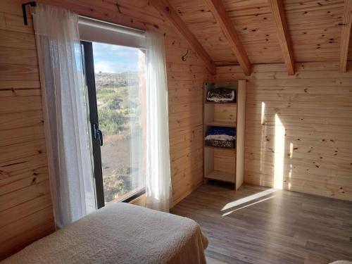 a bedroom with a large window in a wooden cabin at Entre Nubes in Junín de los Andes