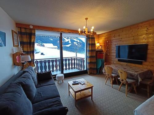 un salon avec un canapé et une grande fenêtre dans l'établissement Sylvia 46, joli studio ensoleillé en centre-ville - Multipass inclu, à Châtel