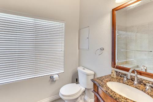 a bathroom with a toilet and a sink and a mirror at 10 Mi to Dtwn Riverside Triplex with Pool in Riverside