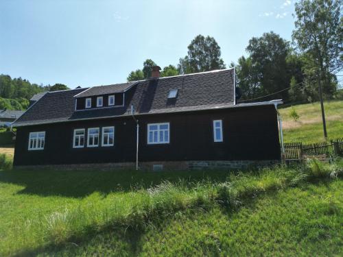 une maison noire sur une colline avec une pelouse dans l'établissement Ferienhaushälfte Gösselberg im Ferienhaus Anno Dazumal, wie zu Großmutters Zeiten, à Klingenthal