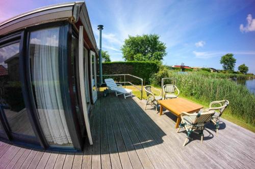 a house with a deck with a table and chairs at Chalet im Hafen mit Angelsteg infrarotsauna in Anjum