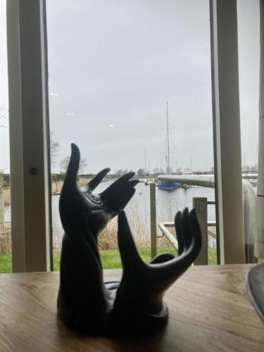 a black cat statue sitting on a table looking out a window at Chalet im Hafen mit Angelsteg infrarotsauna in Anjum