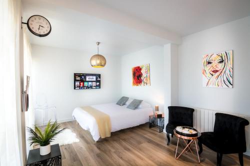 - une chambre avec un lit, une table et une horloge dans l'établissement Art Bay 2 velos parking, à Annecy