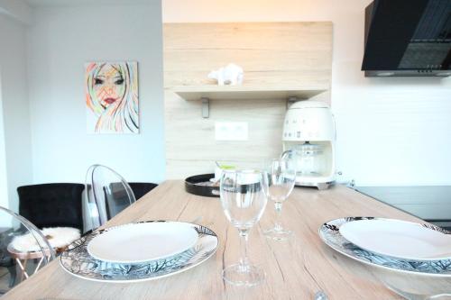 une table en bois avec des assiettes et des verres à vin dessus dans l'établissement Art Bay 2 velos parking, à Annecy