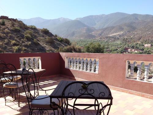 a balcony with tables and chairs with mountains in the background at Ouirgane discovery lodge in Ouirgane