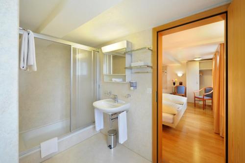 a bathroom with a sink and a shower and a room at Gasthaus Paxmontana in Sachseln