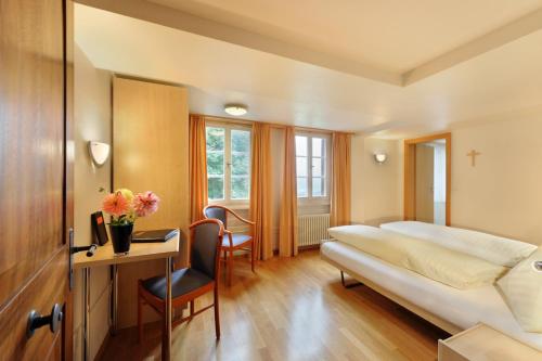 Habitación de hotel con cama y escritorio en Gasthaus Paxmontana, en Sachseln
