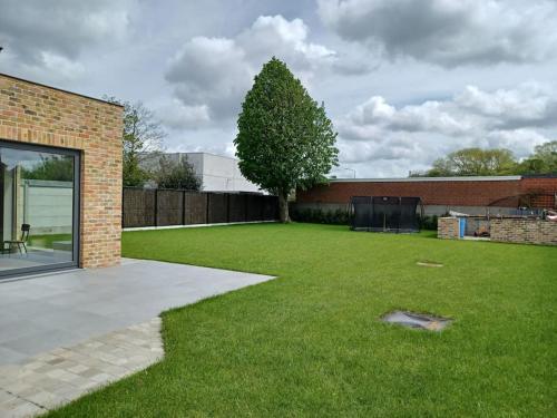 a yard with a tree and a brick building at vakantiehuis Le Libr-air in Koksijde